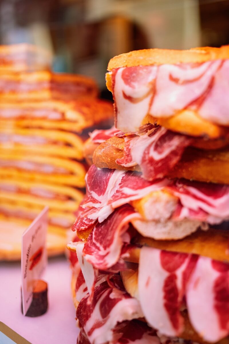 Stacked sandwiches filled with thinly sliced cured ham.